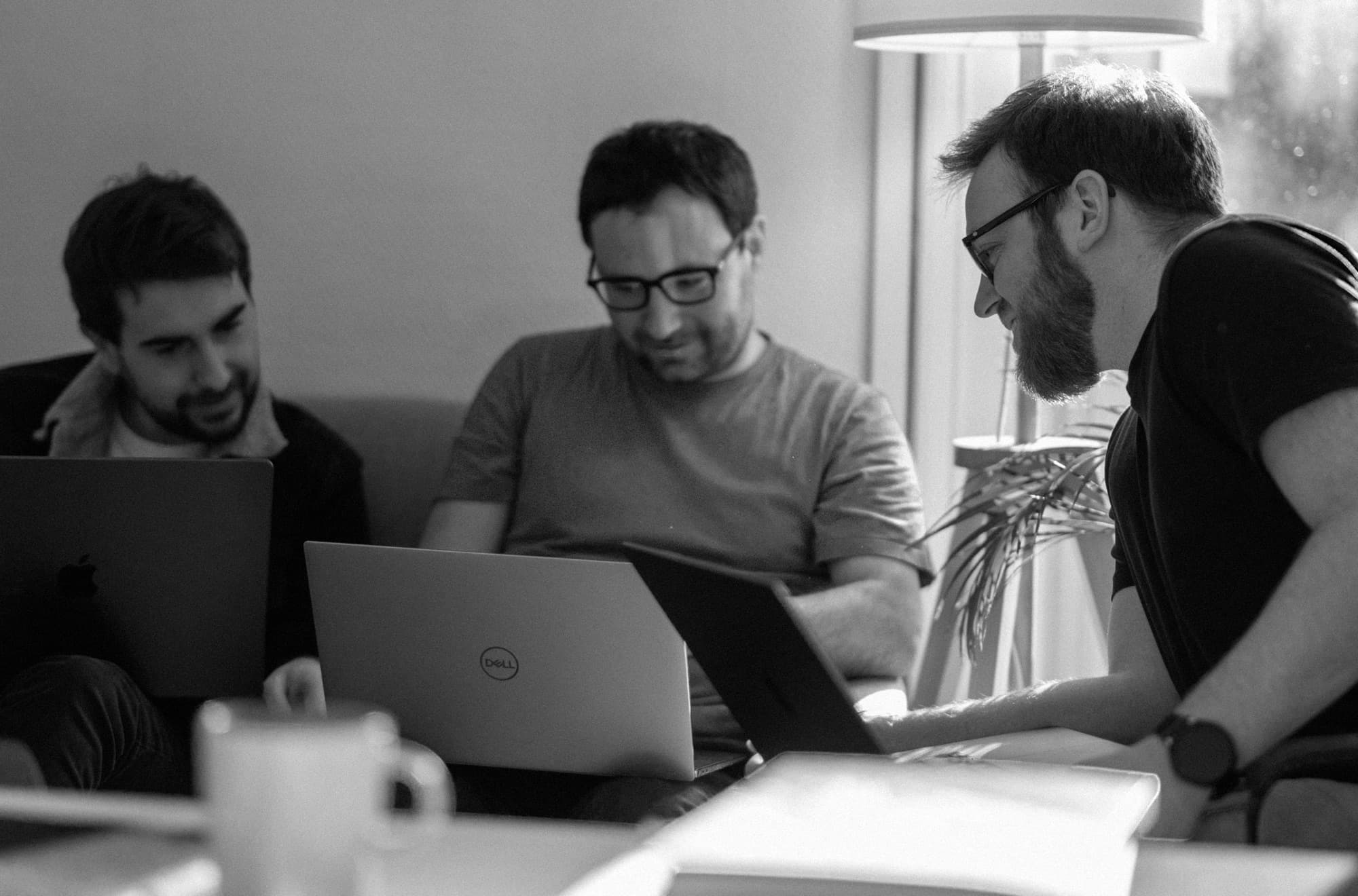 Three of the Another team reading the same screen over their laptops
